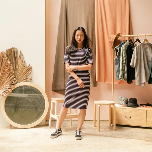 A fashionable woman in a striped dress poses elegantly in a stylish boutique setting.