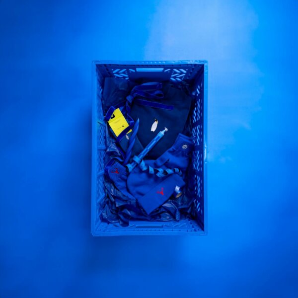 Blue crate filled with various accessories on blue background, photographed from above.