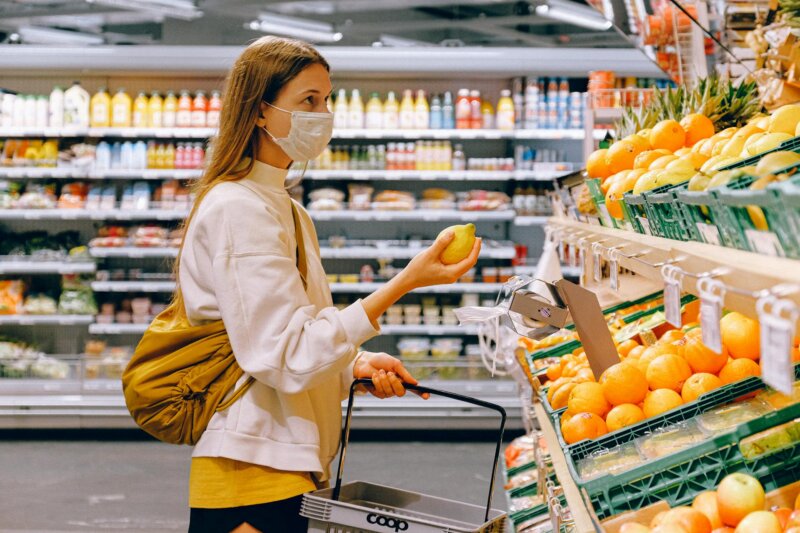 A woman wearing a face mask shops for fruits in a supermarket during a pandemic.