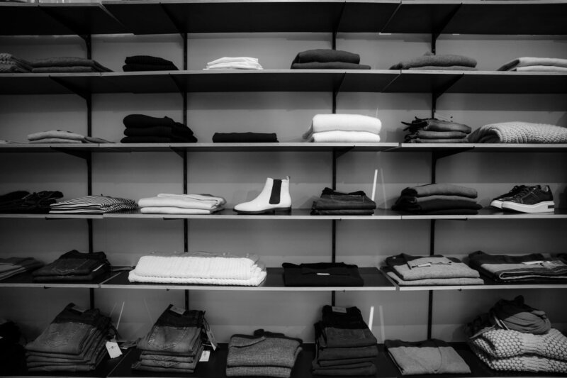 Neatly folded clothing and shoes displayed on shelves in a boutique setting.