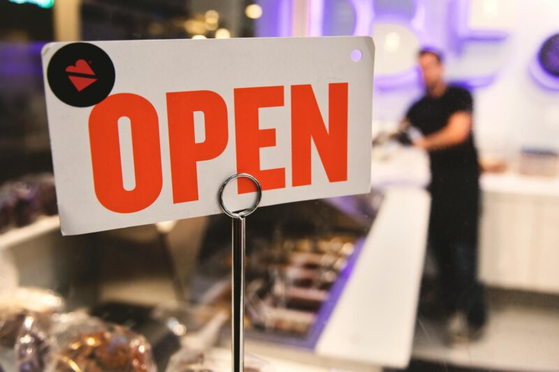 A vibrant open sign in a Los Angeles shop with a blurred figure in the background.