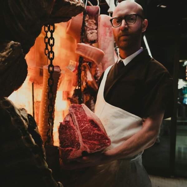 A butcher in Woollahra, Australia, showcasing a raw beef cut in a traditional market setting.