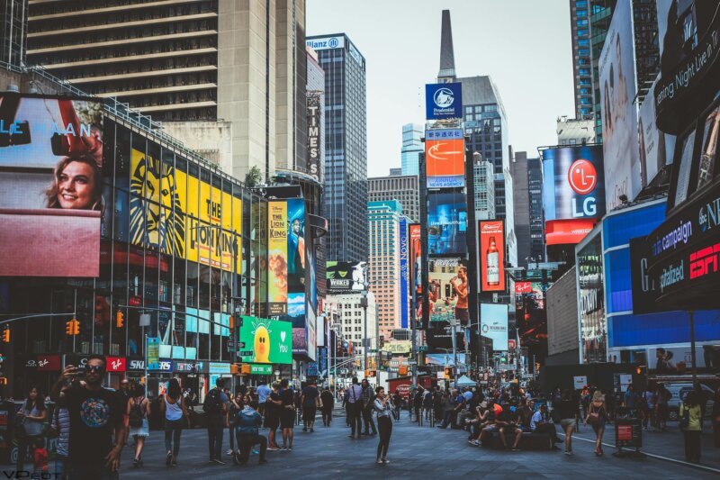 Bustling daytime view of Times Square with crowds, skyscrapers, and iconic billboards in New York City.