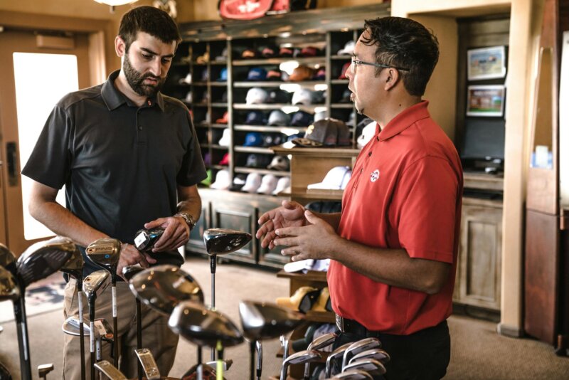 Customer receiving expert advice from salesman on golf equipment in a store.