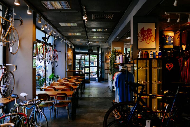 An inviting bike shop and cafe with tables, vintage bikes, and cycling accessories in a modern setting.